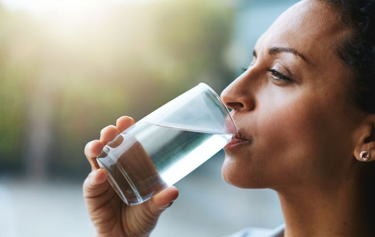 A woman drinking a glass of water.